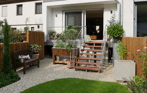 Hauszugang mit Holztreppe, Terrasse und bepflanzten Beeten in naturnaher Gestaltung