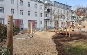 Spielplatz mit Netzen, Holzpfosten und Sandflächen in urbanem Wohnumfeld